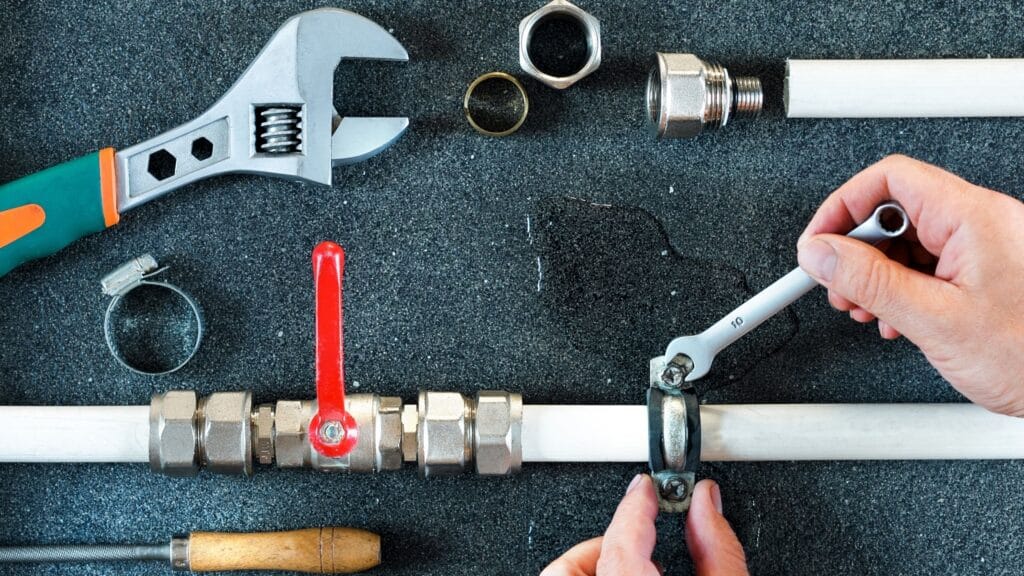 Plumber repairing a pipe valve with an adjustable wrench in Cheltenham