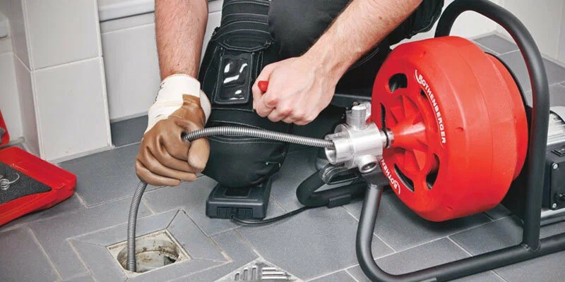 Plumber using a drain-cleaning machine in Cheltenham