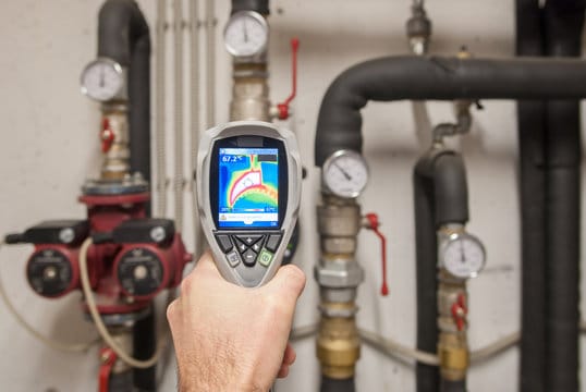 Plumber using a thermal imaging camera to inspect pipes in Cheltenham