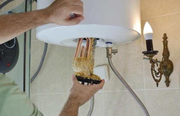 Technician removing mineral buildup from a water heater in Cheltenham