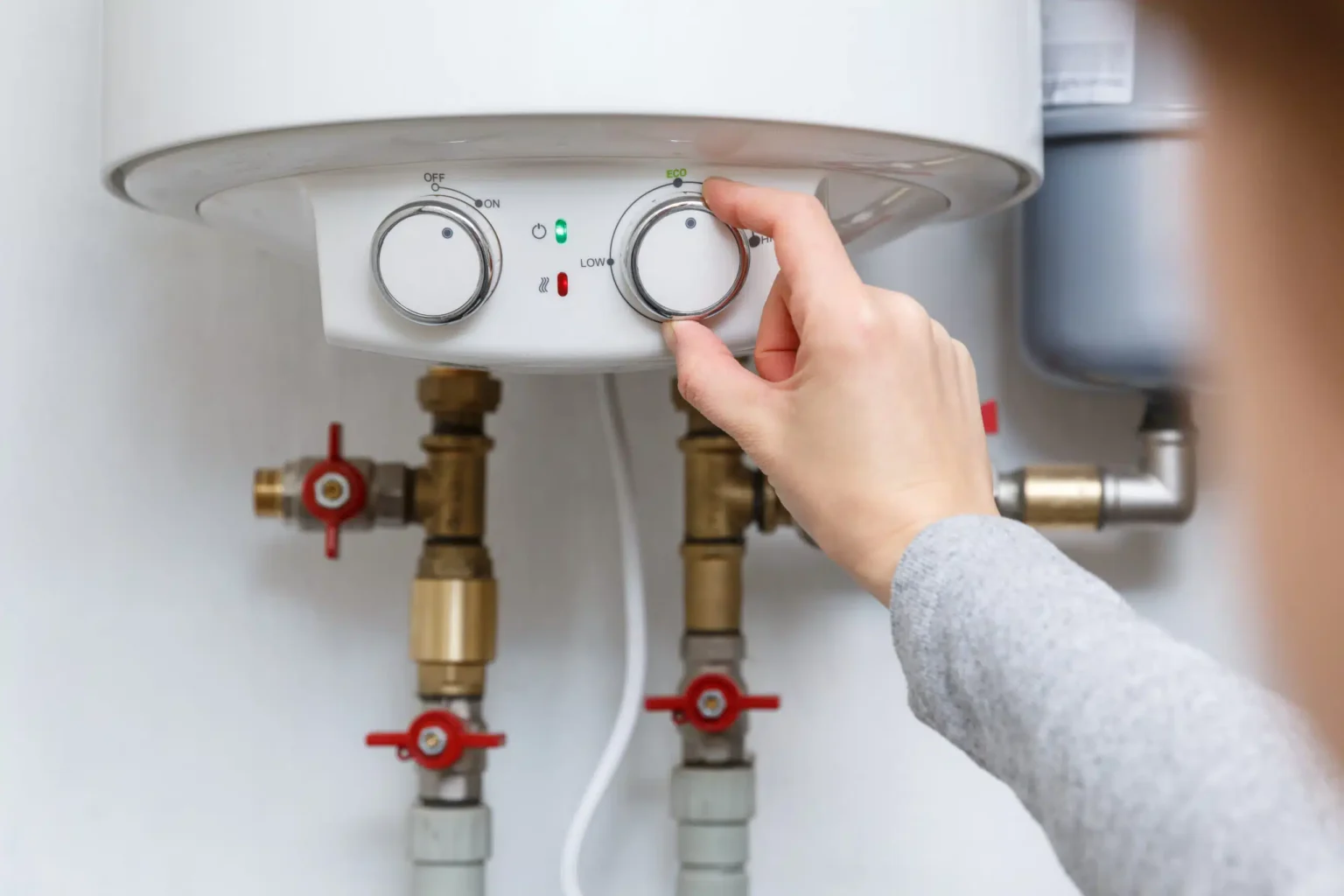 Homeowner adjusting the temperature controls on a water heater in Cheltenham
